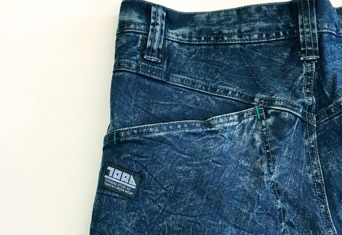 Close-up of denim work pants with back pocket and TOBA brand label
