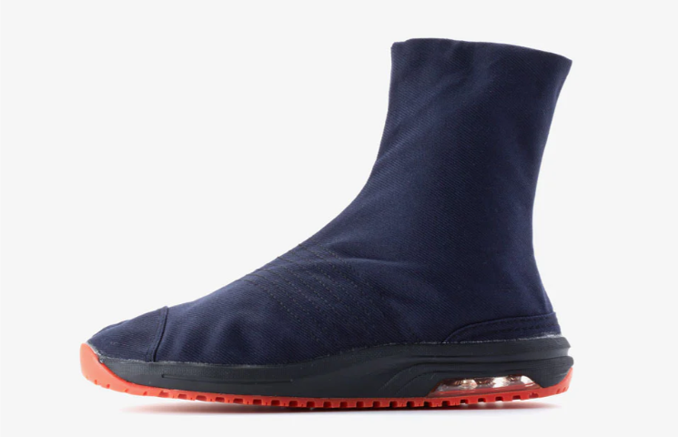 A navy blue split-toe Japanese work boot with a black sole and bright orange tread, shown from the side against a light gray background.