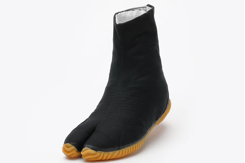 A black split-toe Japanese work boot with a textured yellow rubber sole, shown at an angle against a plain light gray background.
