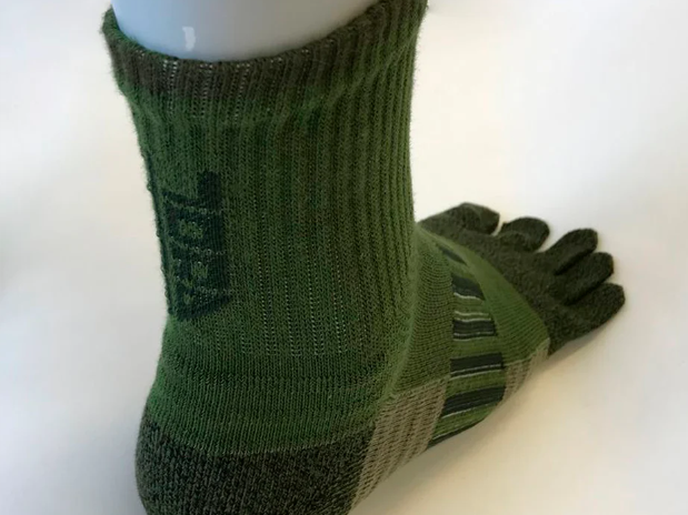 A green five-toe work sock with dark heel and toe sections, shown on a foot against a white background.