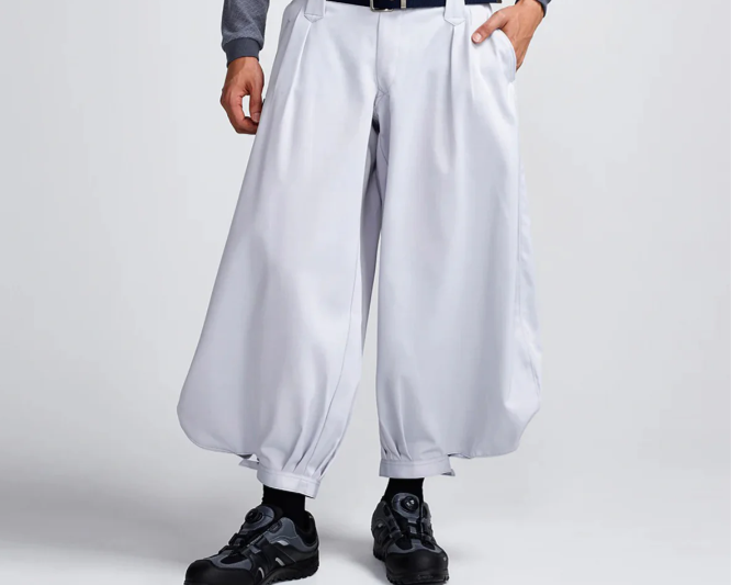 Model wearing white wide-leg Japanese work pants with a black belt and black boots against a plain studio background.