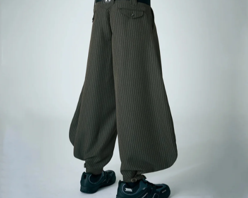 Model wearing dark striped wide-leg Japanese work pants with black boots against a plain studio background.