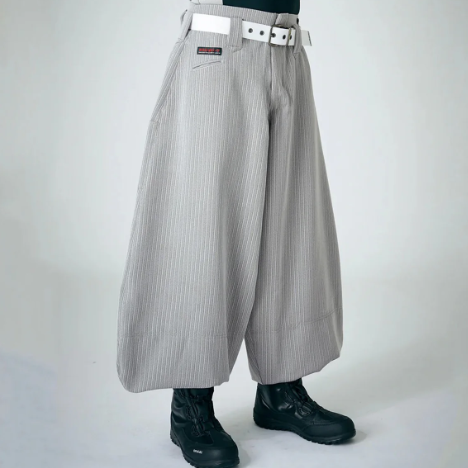 Model wearing light gray striped wide-leg Japanese work pants with a white belt and black boots against a plain studio background.