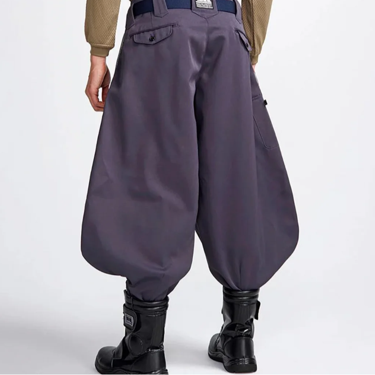 Model wearing dark gray baggy Japanese work pants with a back pocket, navy belt, and black boots, shown from the rear against a plain white background.