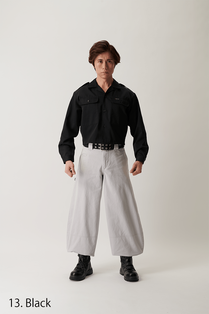 Model posing with hands on hips in black short open shirt