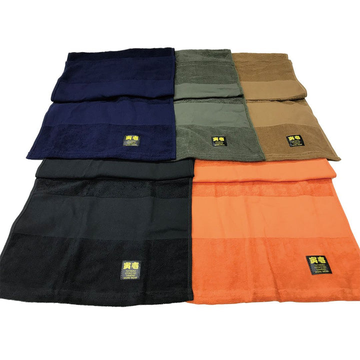Flat lay of Toraichi towels in orange, black, and navy showcasing Japanese workwear design