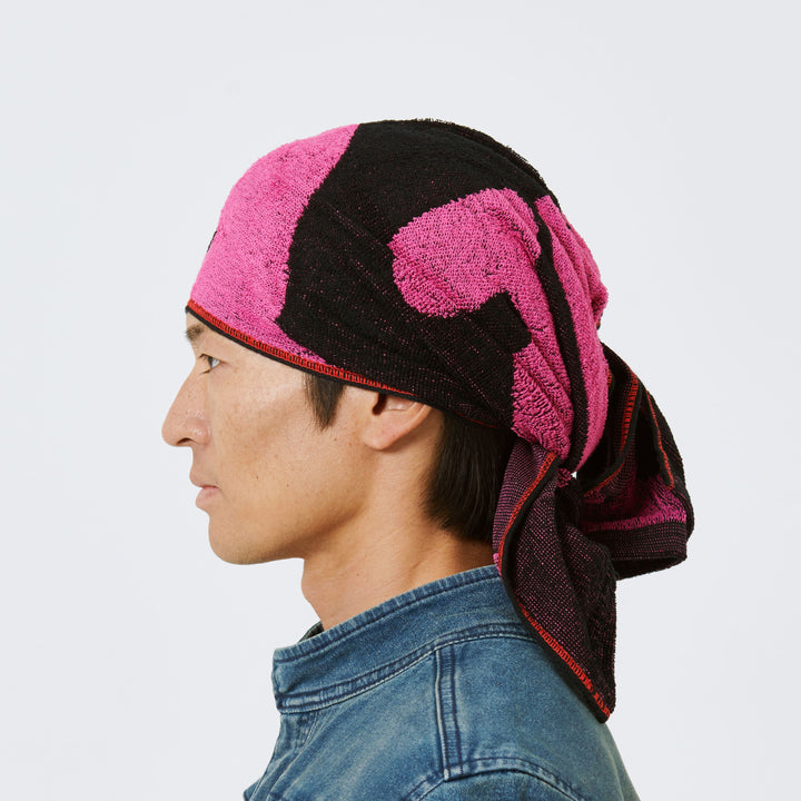 Side profile of model wearing Toraichi red-edged towel tied as head wrap